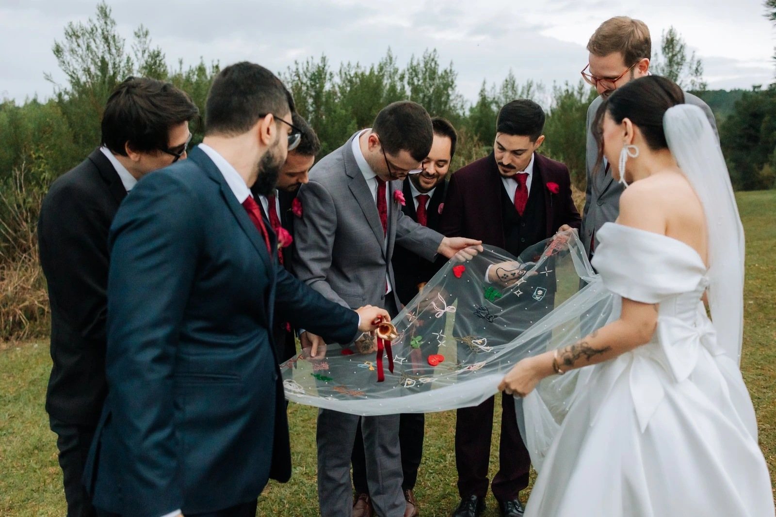 Padrinhos segurando a cauda do véu bordado à mão, no ensaio do casamento